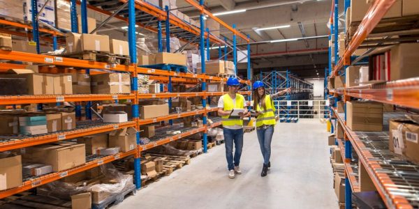 two-warehouse-workers-walking-distribution-storage-area-discussing-about-logistics-organization_342744-1541